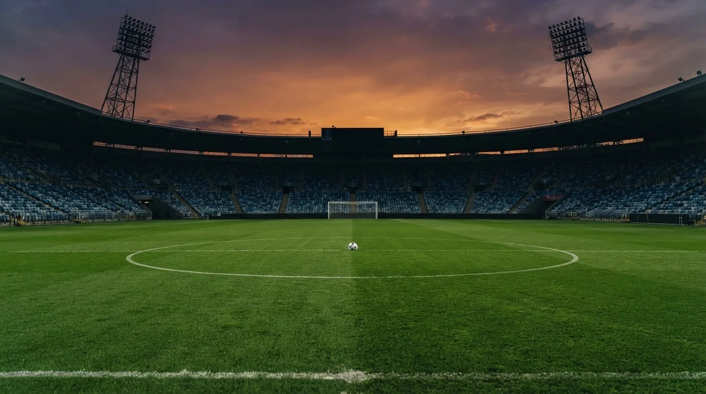 An empty football stadium with floodlight masts at dusk