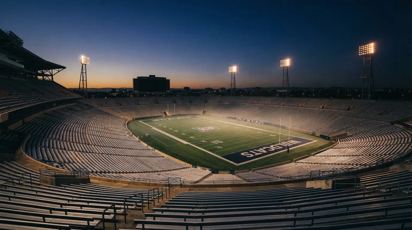 An empty football stadium with floodlight masts at dusk