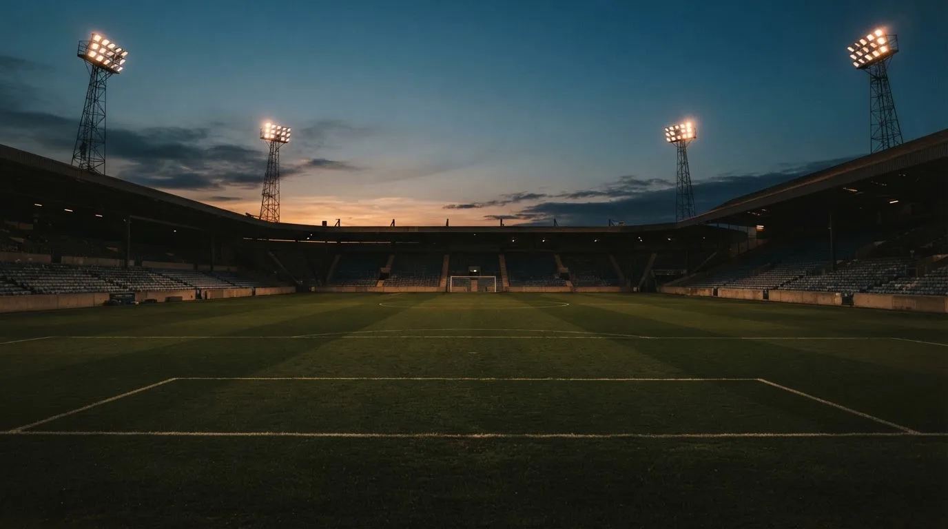 An empty football stadium with floodlight masts at dusk