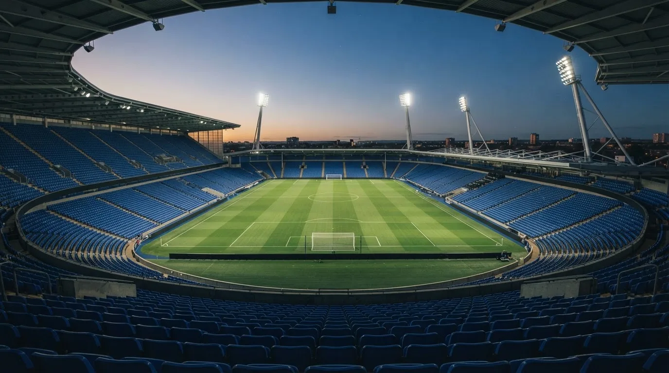 An empty football stadium with floodlight masts at dusk