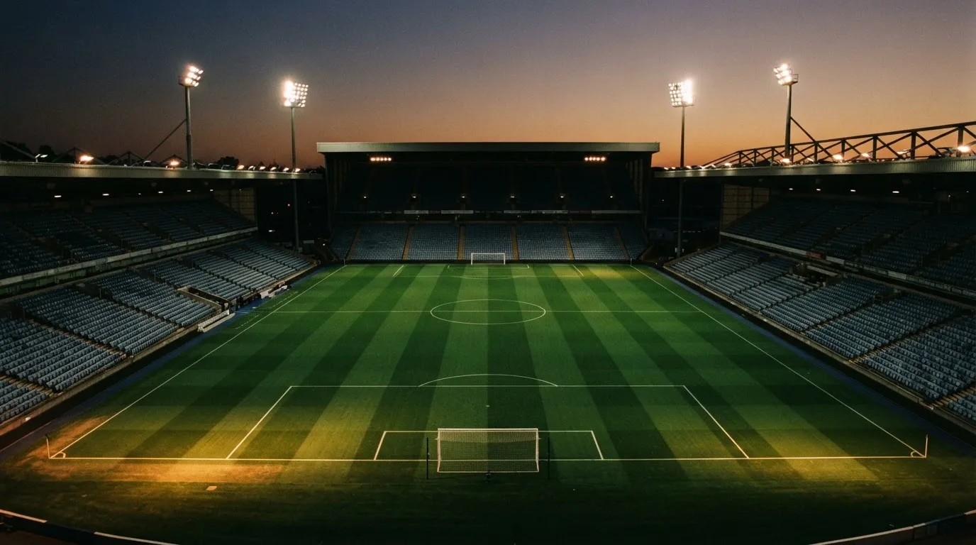 An empty football stadium with floodlight masts at dusk