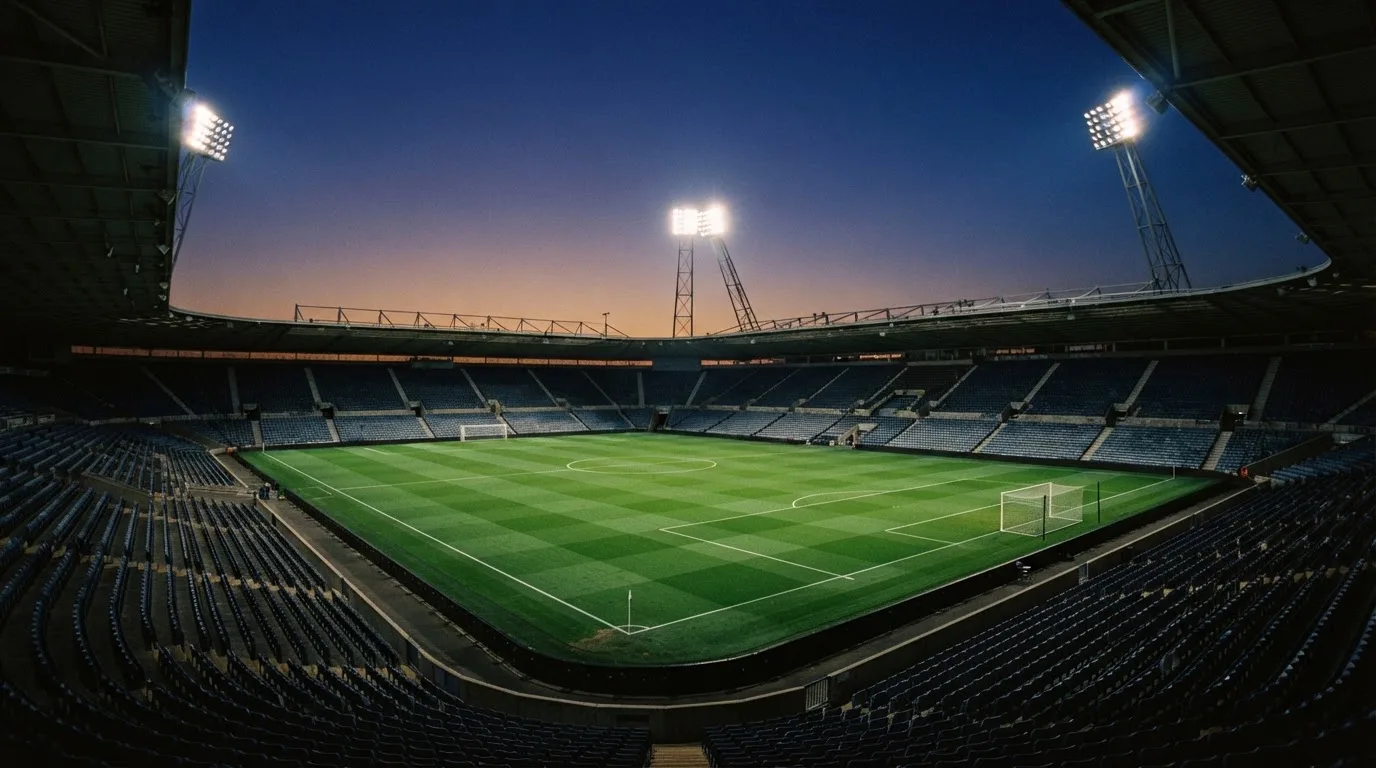 An empty football stadium with floodlight masts at dusk