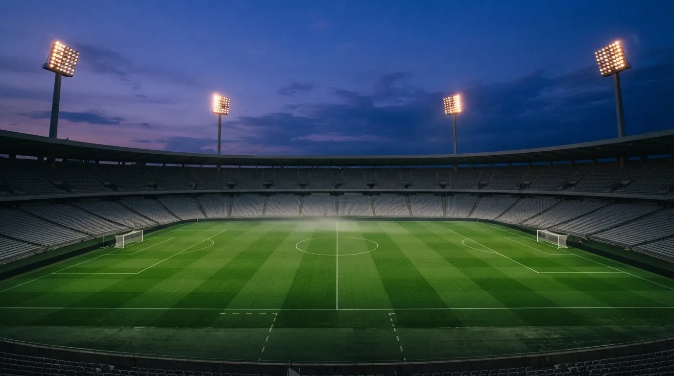 An empty football stadium with floodlight masts at dusk