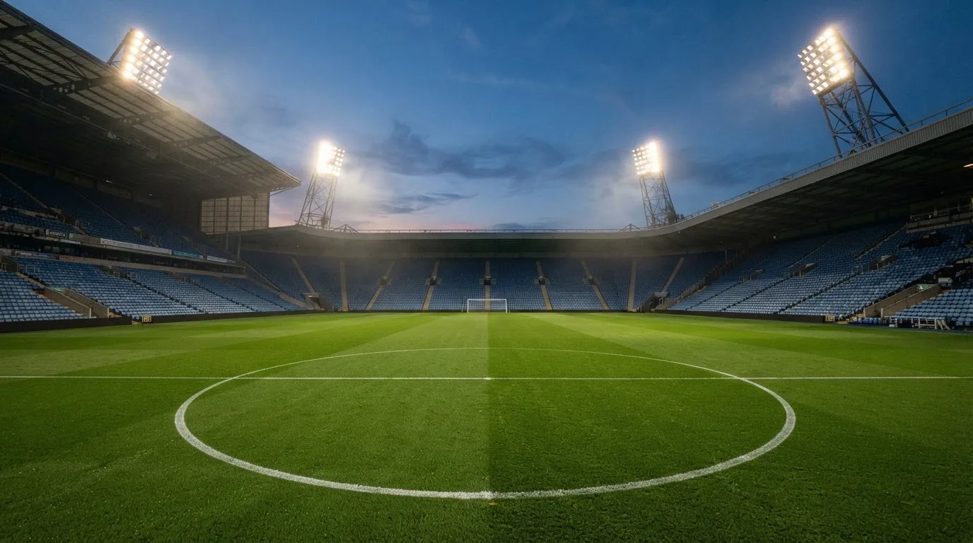 An empty football stadium with floodlight masts at dusk