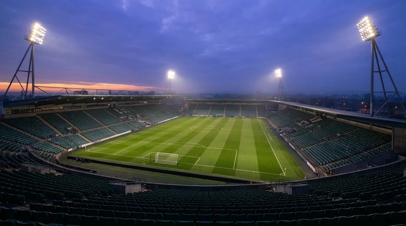 An empty football stadium with floodlight masts at dusk