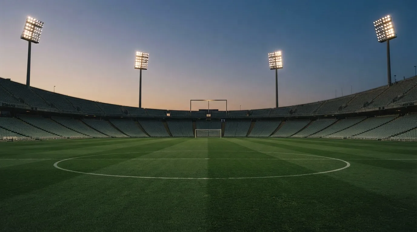 An empty football stadium with floodlight masts at dusk