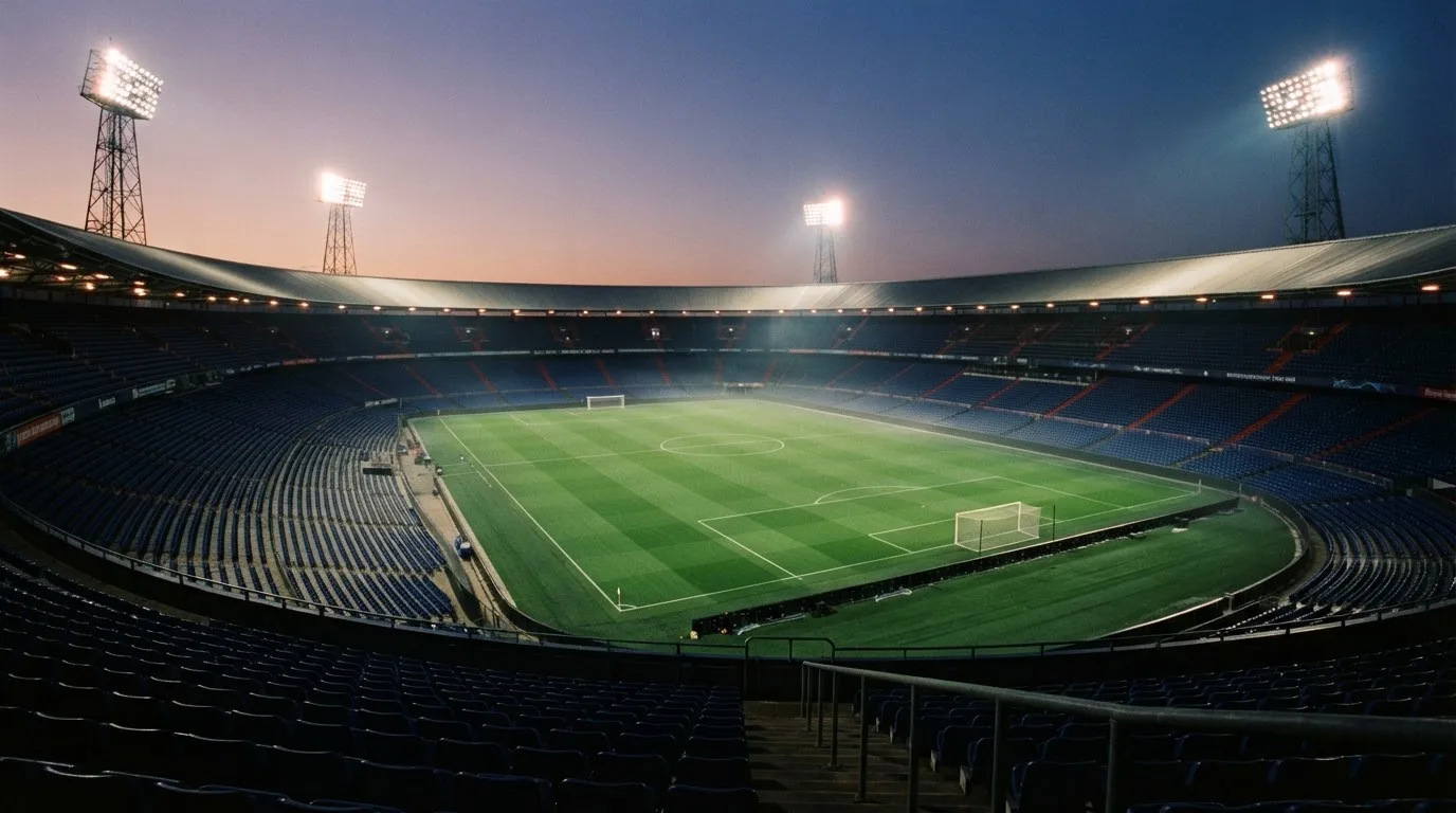 An empty football stadium with floodlight masts at dusk