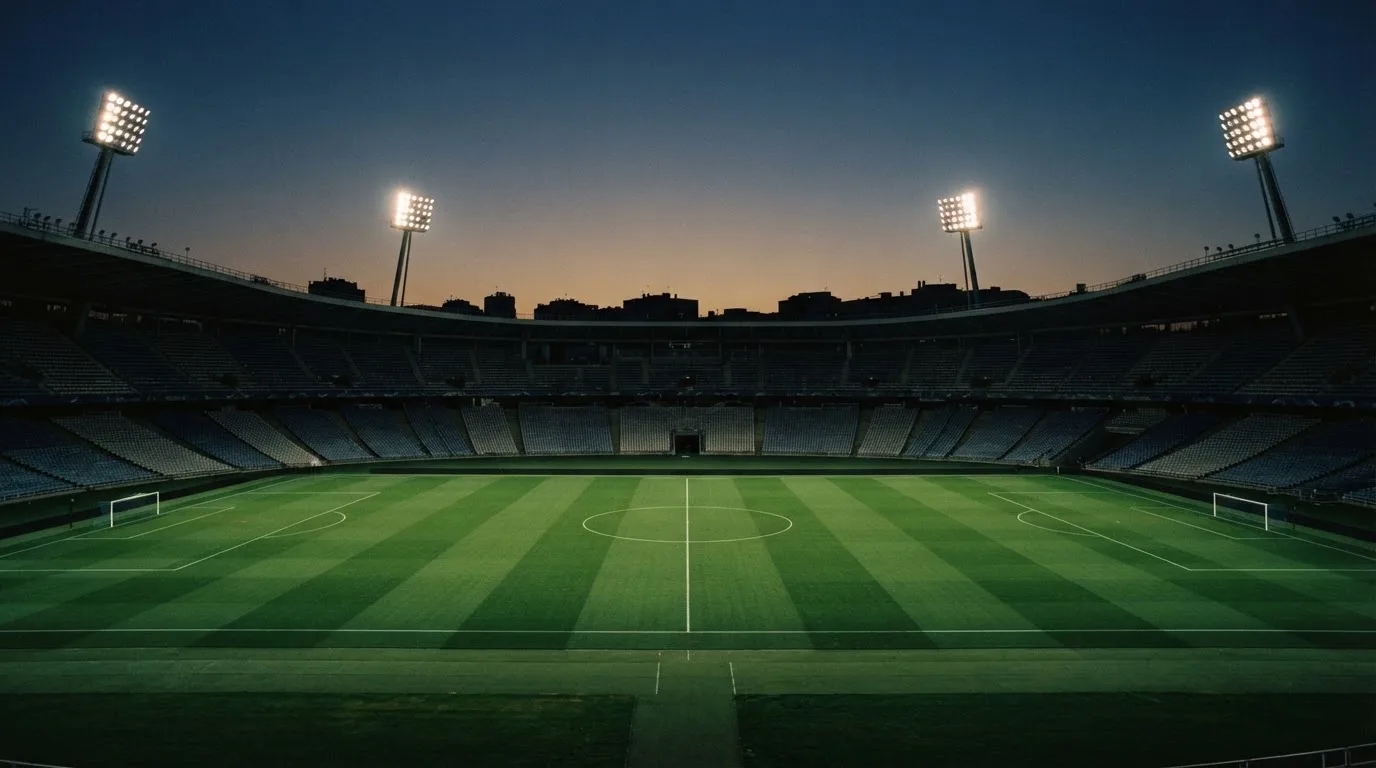 An empty football stadium with floodlight masts at dusk