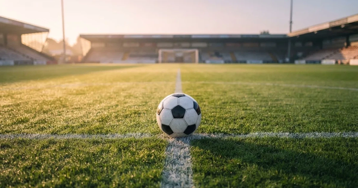A ball on the centre spot of a grass pitch in morning light