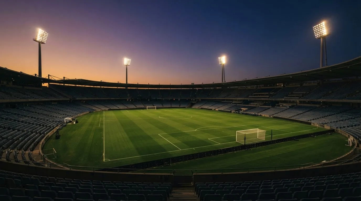 An empty football stadium with floodlight masts at dusk