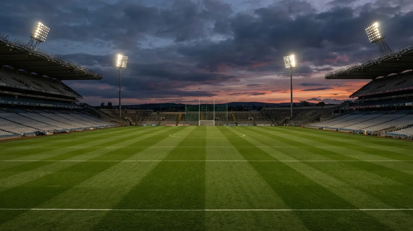 An empty football stadium with floodlight masts at dusk