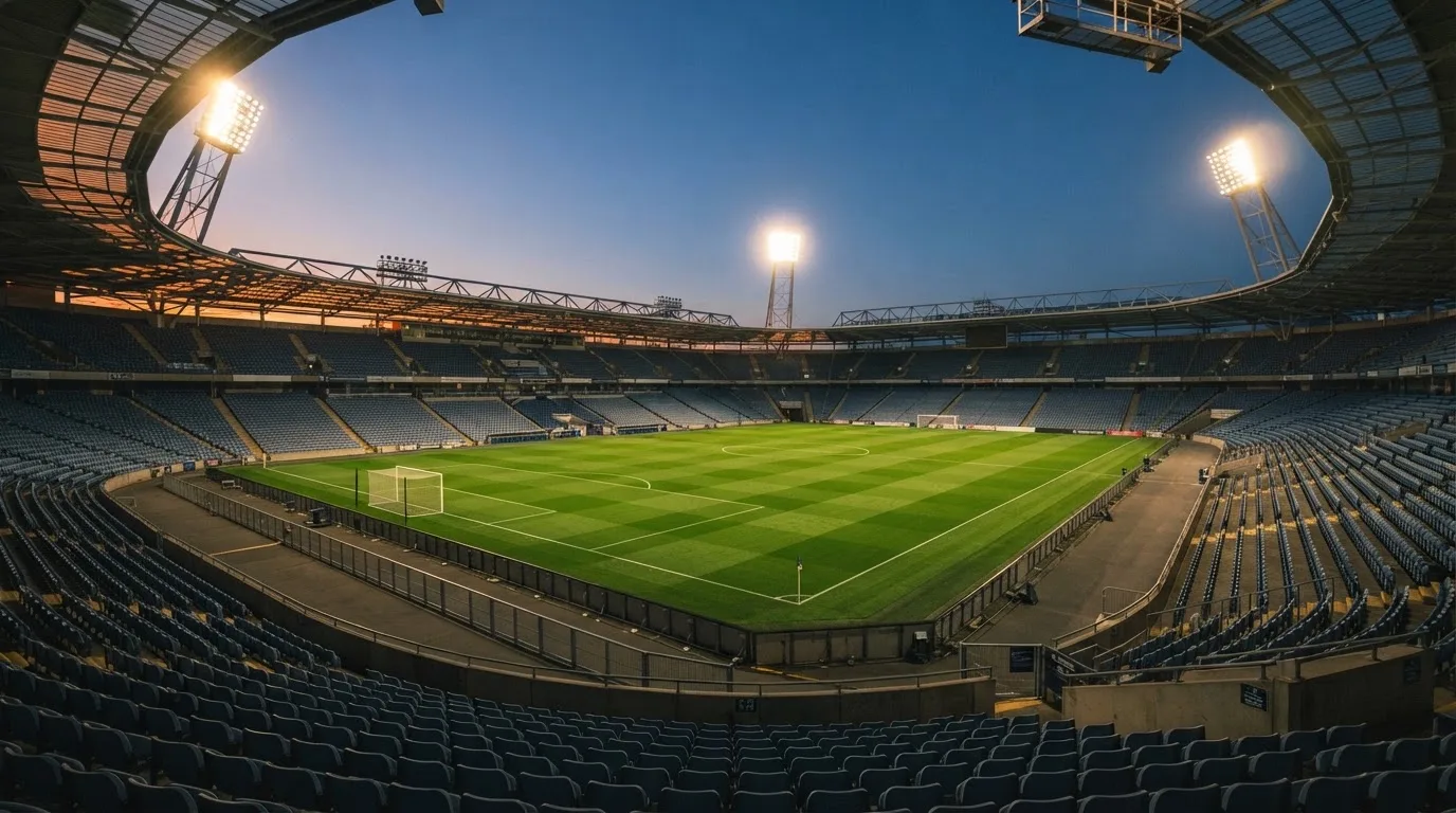 An empty football stadium with floodlight masts at dusk